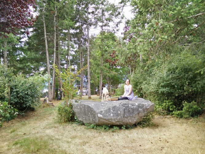 A guest sitting on a boulder among the trees at Bradsdadsland